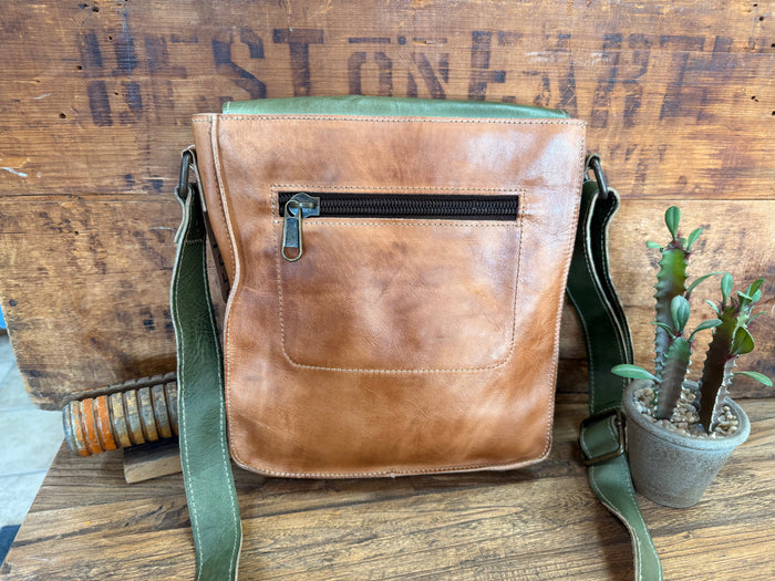 Back view of tan leather crossbody purse with zip pocket and green adjustable shoulder strap.