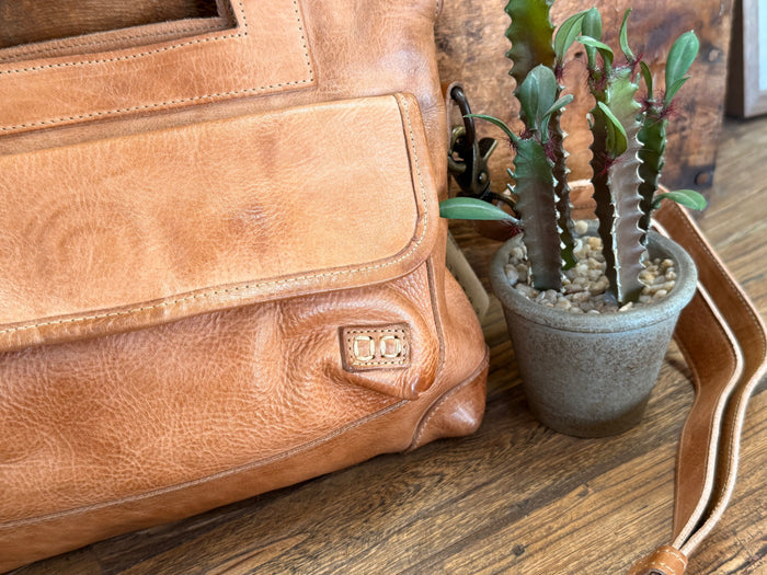 Tan leather crossbody purse side with stitched panel and small logo patch