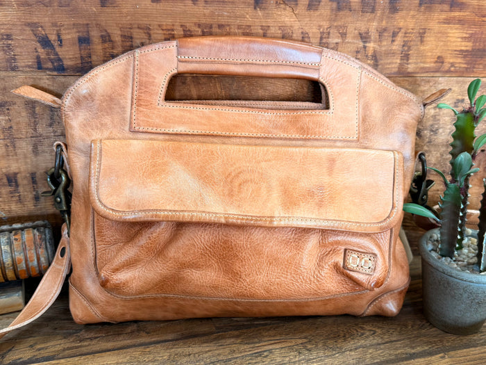 Tan leather crossbody purse front with flap pocket, dark metal hardware, and strap
