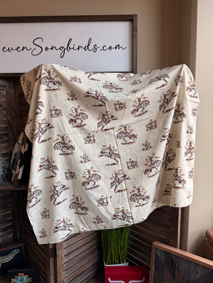 Wild rag scarf draped over stand, cream fabric with repeating brown western figures