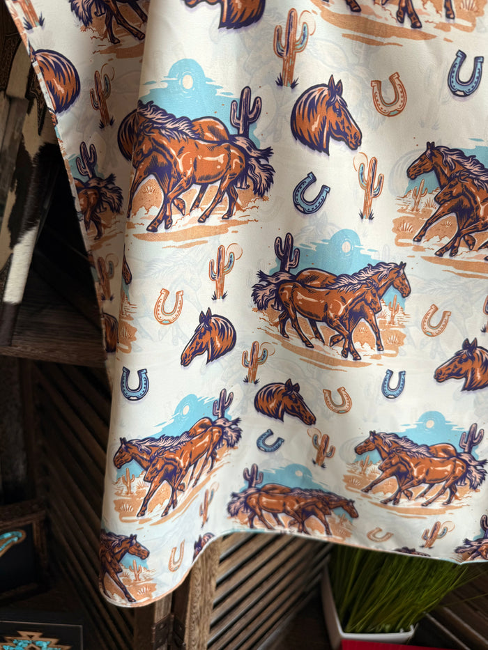Wild Rag scarf close-up, illustrated horses and horseshoes on light fabric with blue sky