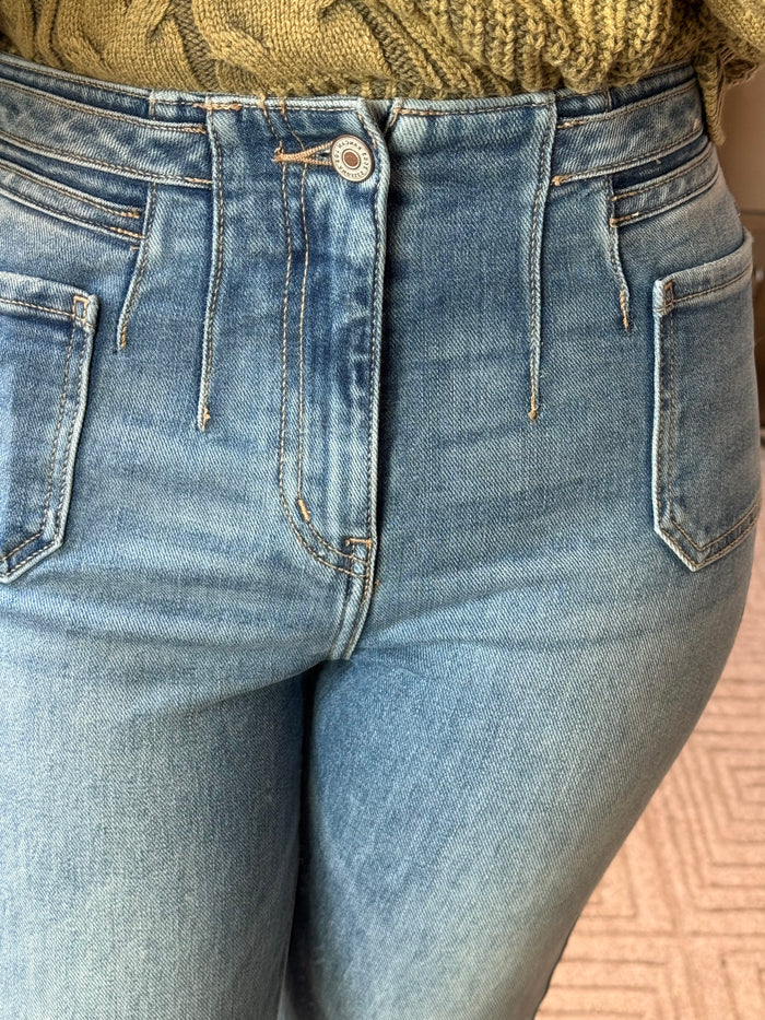 Women's denim jeans close-up: button waistband, belt loops, patch pockets
