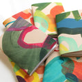 Five Ark handpainted A6 leather sketchbooks in vibrant colors are scattered in a pile on a white background, creative supplies.