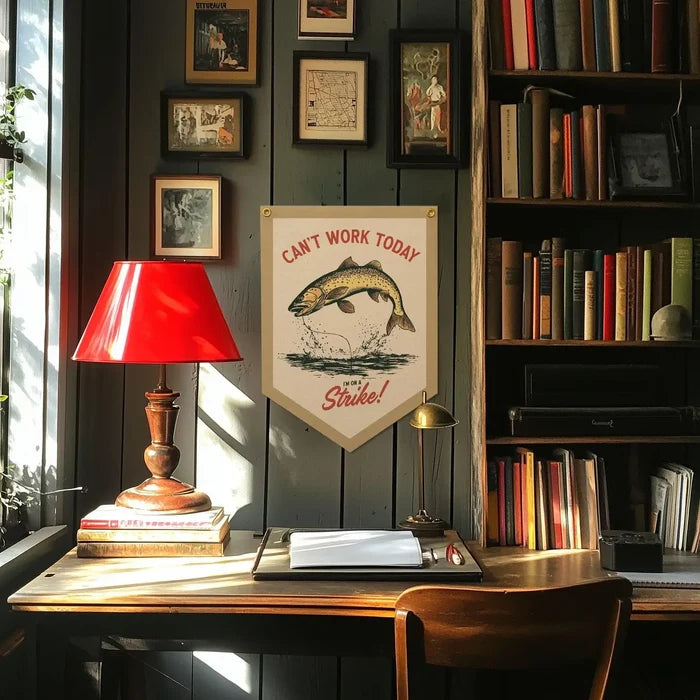 Modern workspace with red lamp, stacked books, and Cant Work Today Im On Strike Benoit pennant banner on desk.