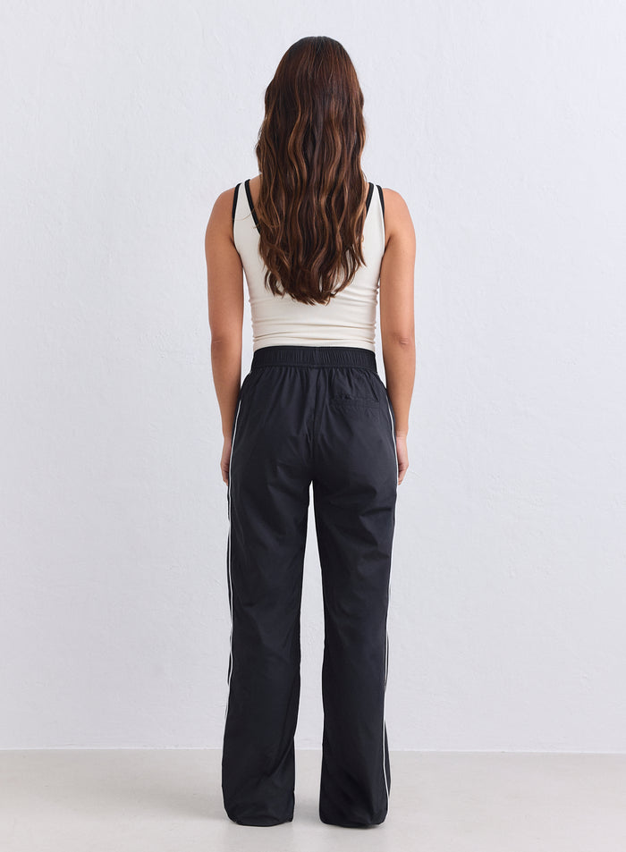 Mustat rennot aim'n Balance Tracksuit Pants -housut valkoisilla sivuraidoilla takaapäin. [S-165cm]