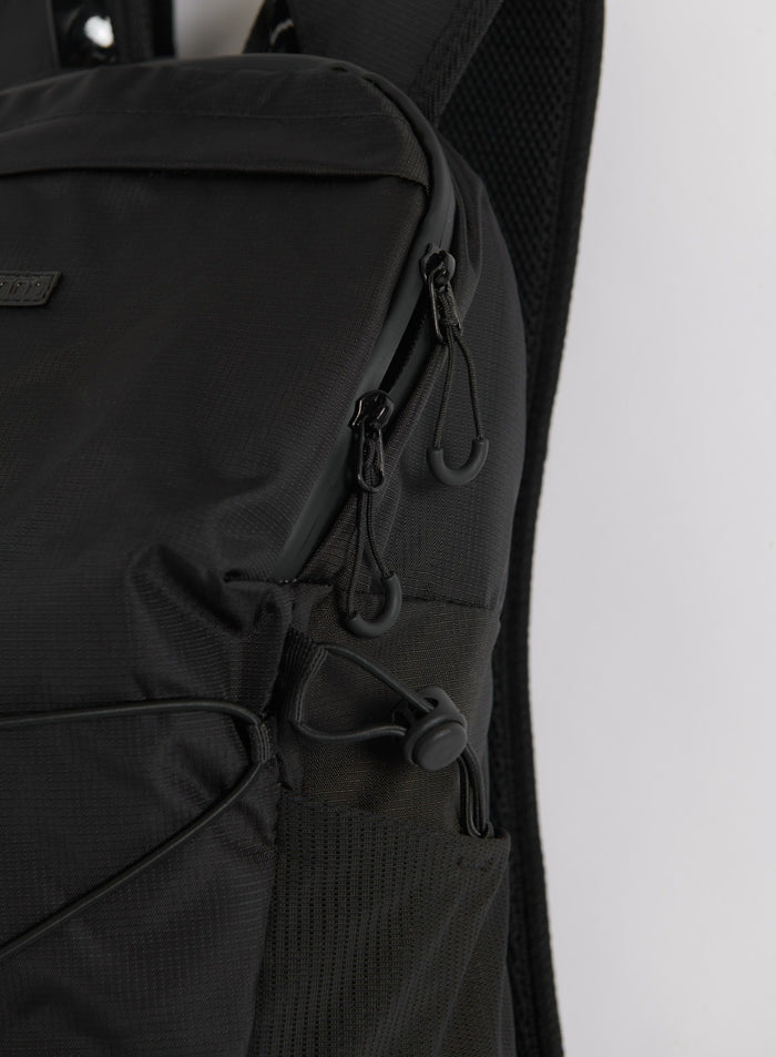 Lähikuva mustan Outdoor Daypack -repun vetoketjusta ja sivutaskun yksityiskohdista