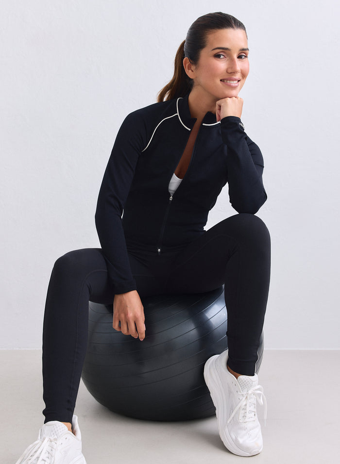 Musta aim'n Shape Seamless Contrast Zip Jacket valkoisilla tereillä mallin päällä jumppapallolla. [XS-165cm]