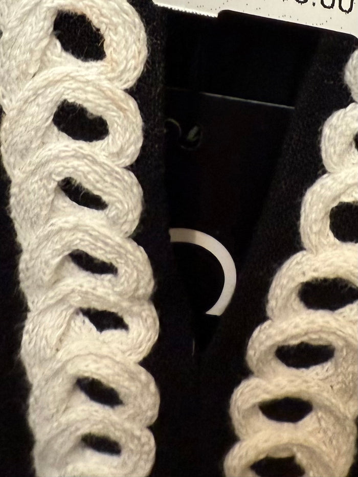 Black shirt with bold white embroidered trim near neckline