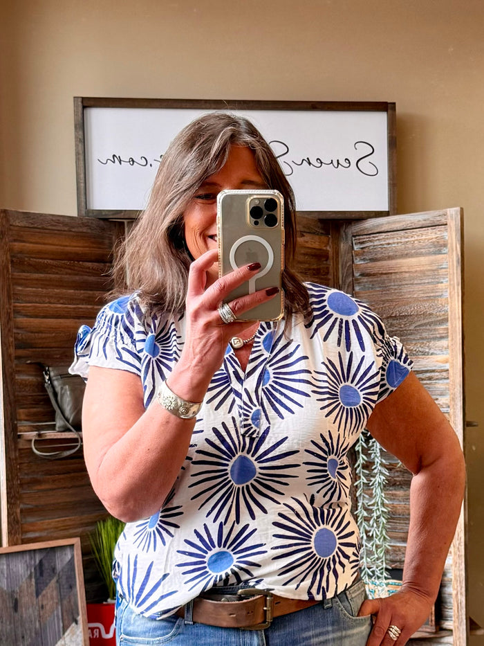 V-neck short-sleeve shirt with blue circular sunburst print on white fabric