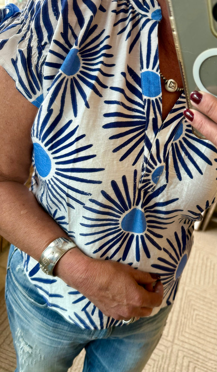 Close-up of blue sunburst print V-neck short-sleeve shirt on white fabric