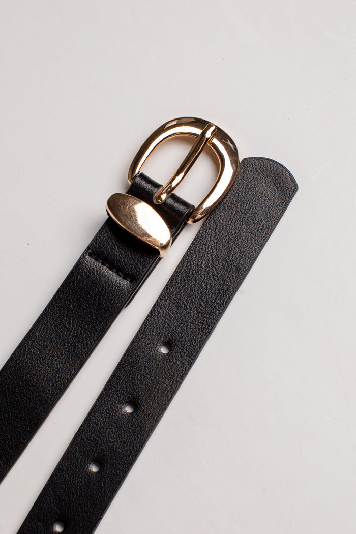 A close-up of a black leather belt strap with a polished gold-tone metal buckle, laid diagonally on a light gray background.