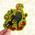 Hand holding Curlworks Turkey Vinyl Sticker with red feet, fall leaves, berries, and an apple on green background. Perfect decor.