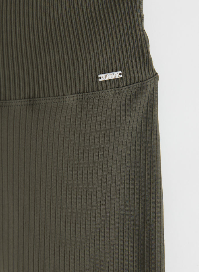 Lähikuva tummanvihreiden Ribbed Seamless Flare Petite -trikoiden vyötärönauhasta, jossa näkyy metallinen aim'n-logolappu