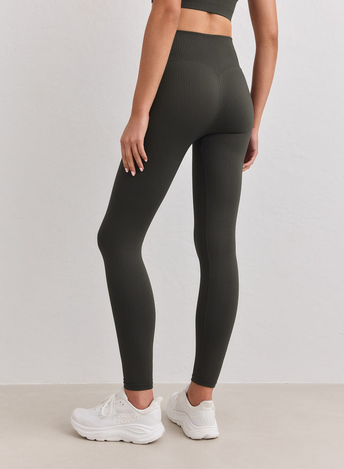 Malli takaa päällään Dark Ivy Ribbed Seamless Tall Tights -trikoot ja valkoiset lenkkarit