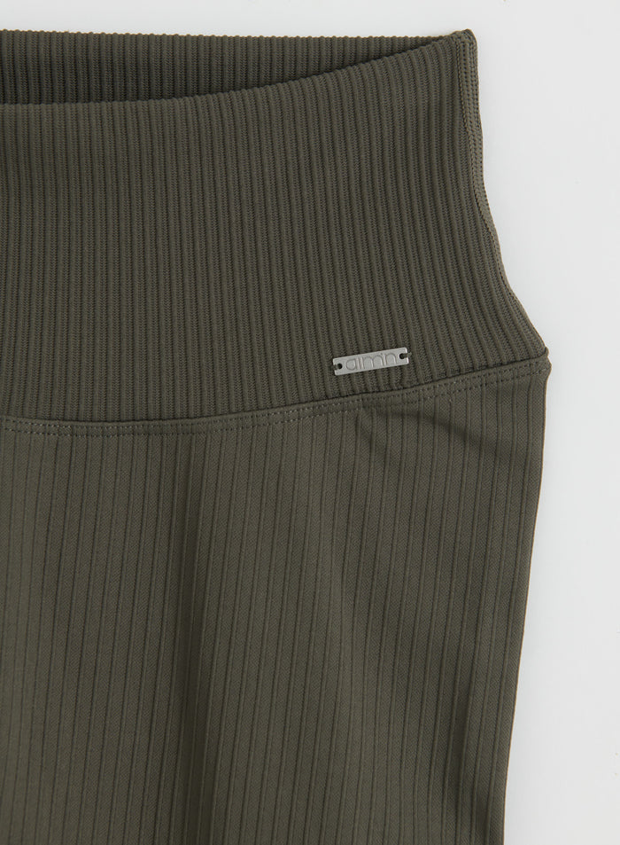 Lähikuva Dark Ivy Ribbed Seamless Tall Tights -trikoiden vyötärönauhasta ja metallisesta logomerkistä