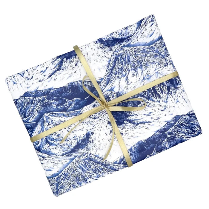 Rectangular gift wrapped in Discover & Draw’s Mountains Gift Paper - Navy, finished with a shiny gold ribbon bow for gifting.