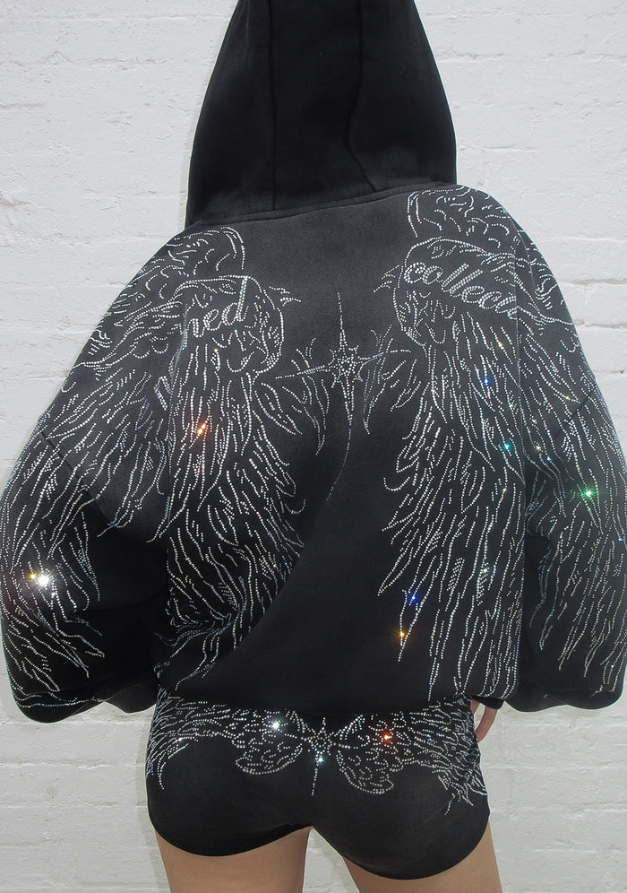 Back view of a washed black hoodie with a rhinestone wing design and detachable fur trim.