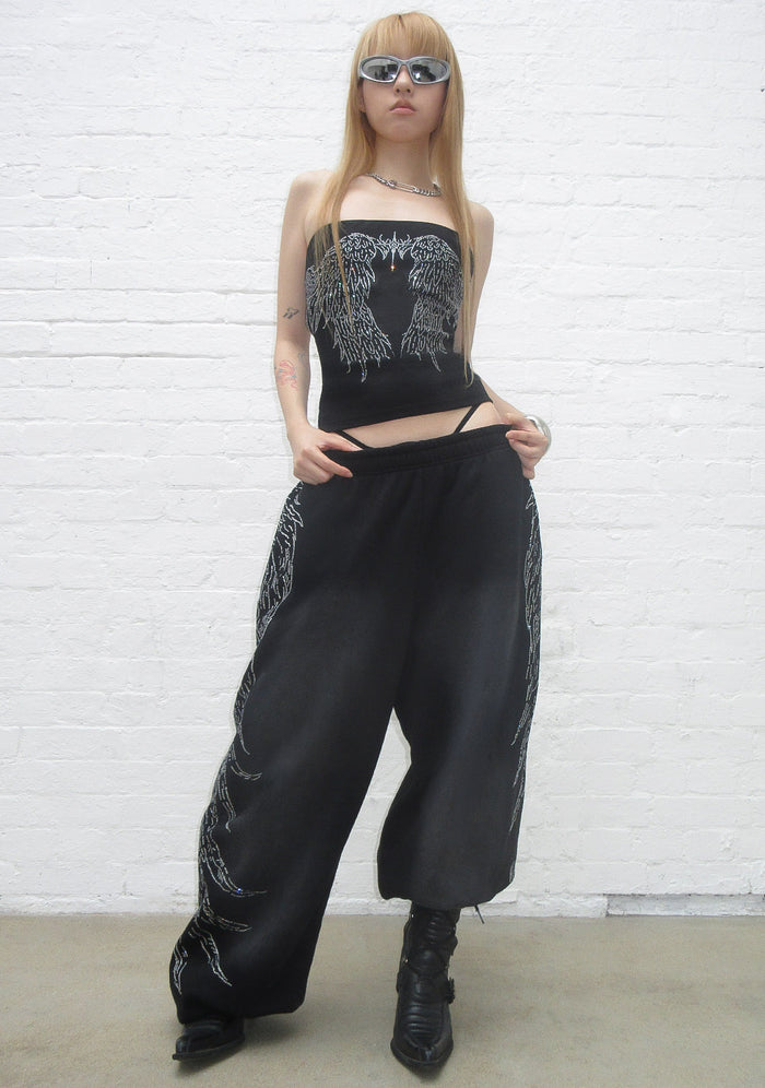 Model wearing fallen rhinestone oversized sweatpants in washed black with rhinestone detailing on the side.