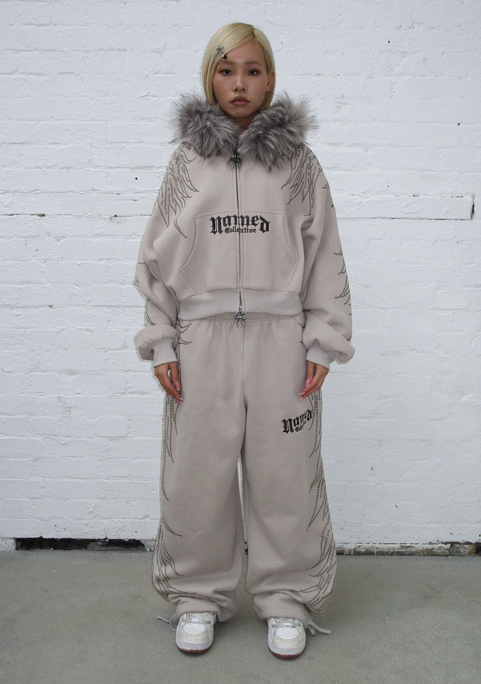 Model wearing bone sweatpants featuring studs and embroidered logo, front view.
