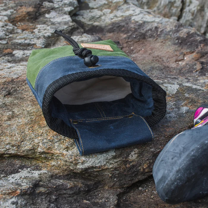 Fernweh UK Scree/Moss/Storm chalk bag open on rocks, next to climbing shoe toe, for rock climbing and bouldering gear.