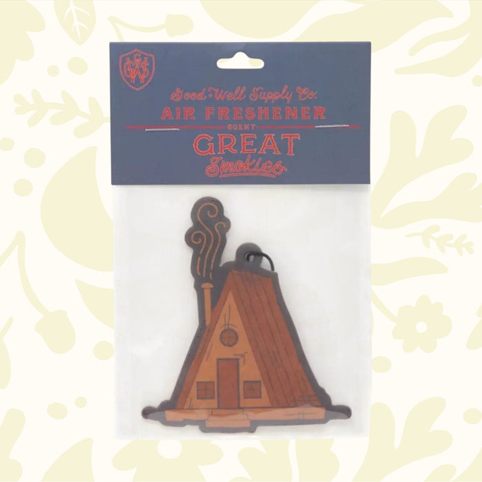 Introducing the Good & Well Supply Co Hangable Air Freshener - Great Smokies: a delightful auto fragrance designed to resemble a wooden cabin with smoke wafting from its chimney. This charming air freshener, perfect for adding a rustic touch to your car, proudly supports the National Park Foundation and is ideal for nature enthusiasts.