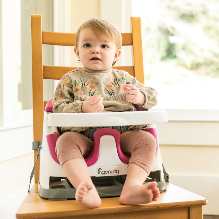Ingenuity Baby Base 2-in-1 booster seat in Pink Flambe for infants and toddlers with removable tray and adjustable straps