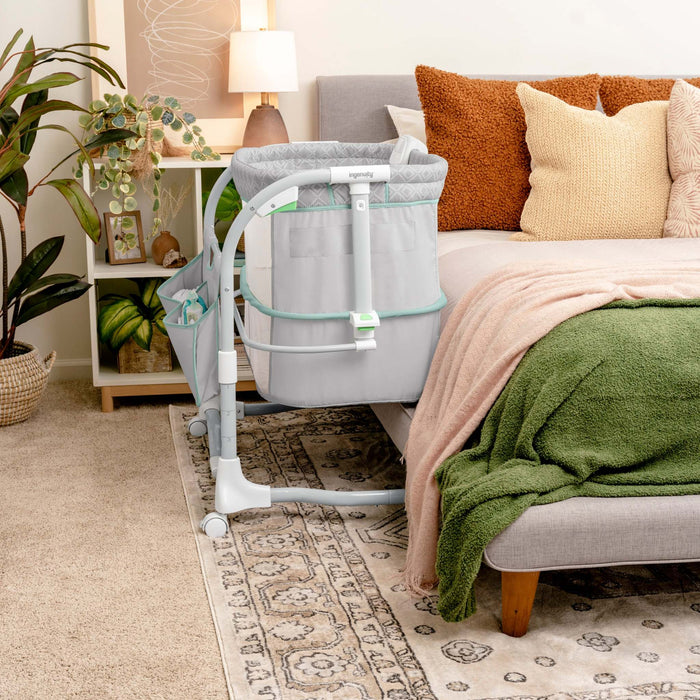 Ingenuity Dream & Grow Bedside Bassinet with breathable mesh sides and adjustable height near bed