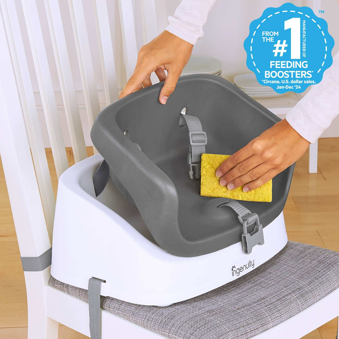 Ingenuity SmartClean Toddler Booster Seat in slate color with removable foam insert and 3-point harness attached to dining chair