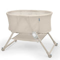 Ingenuity Snooze & Stow™ Easy-Folding Bassinet in sand color with sound, light, and vibration features for baby sleep and portability