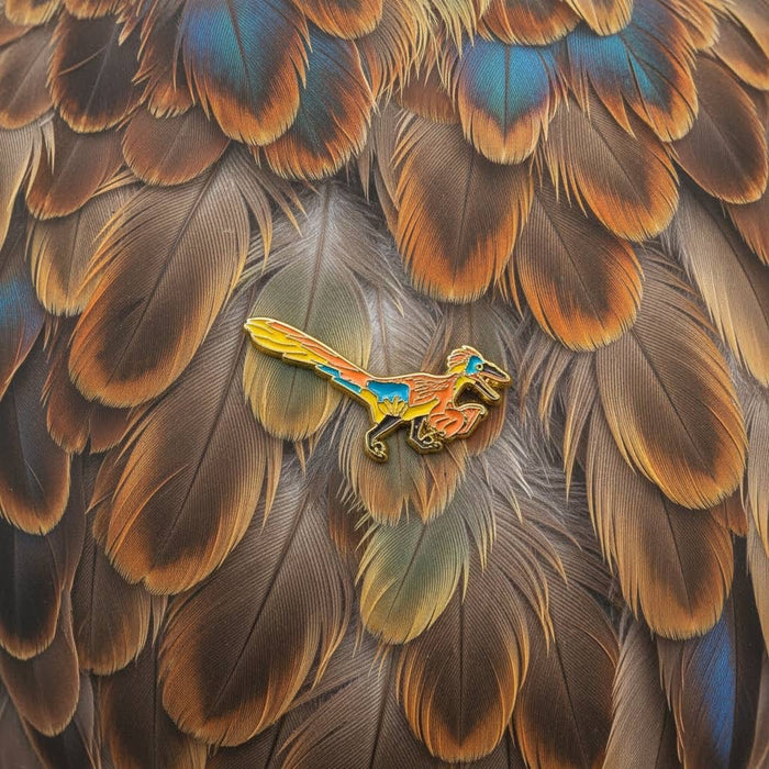Forager Provisions LTD James Barker Raptor enamel pin badge with gold metal finish, pinned on brown bird feathers.