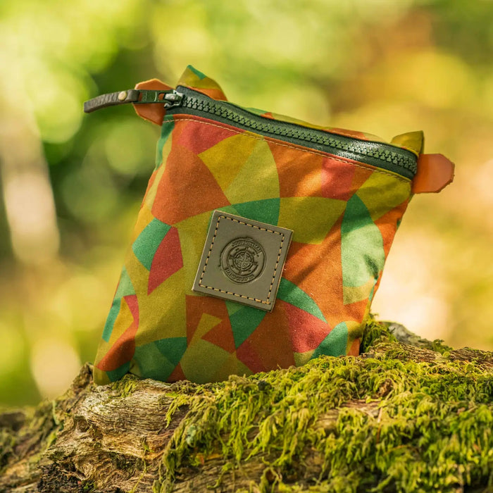 Forager Provisions LTD Journeyman Craft camo zipper pouch made from reclaimed fabric, sitting on a mossy log.