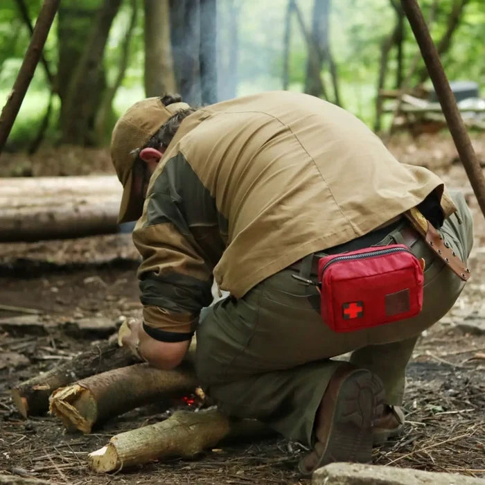 Adventurer lighting campfire, sporting Journeyman Craft Handcraft First Aid Kit Belt, perfect for camping safety gear.