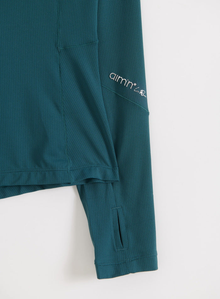 Lähikuva hihojen yksityiskohdista, joissa näkyy huomaamaton aim'n-logo lagoon-värisessä Running Zip Long Sleeve -paidassa