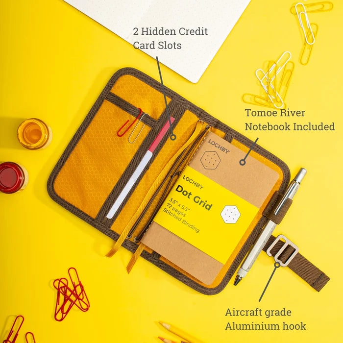 Lochby Mini Field Journal brown refillable notebook set with pens and clips, displayed on a vibrant yellow background.