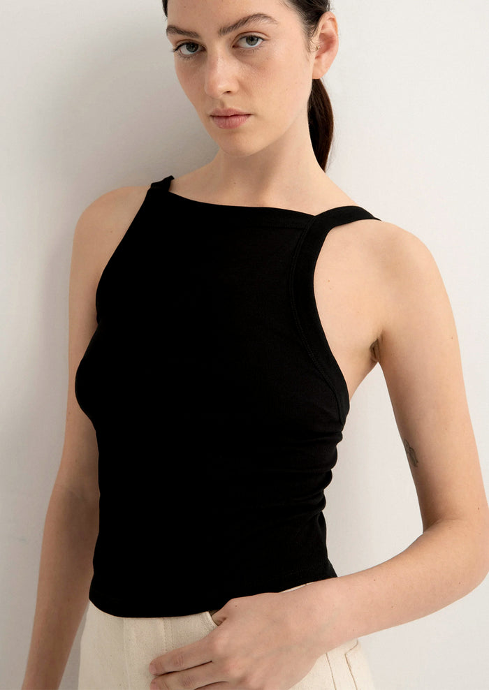 Woman wearing a black sleeveless top against a plain background