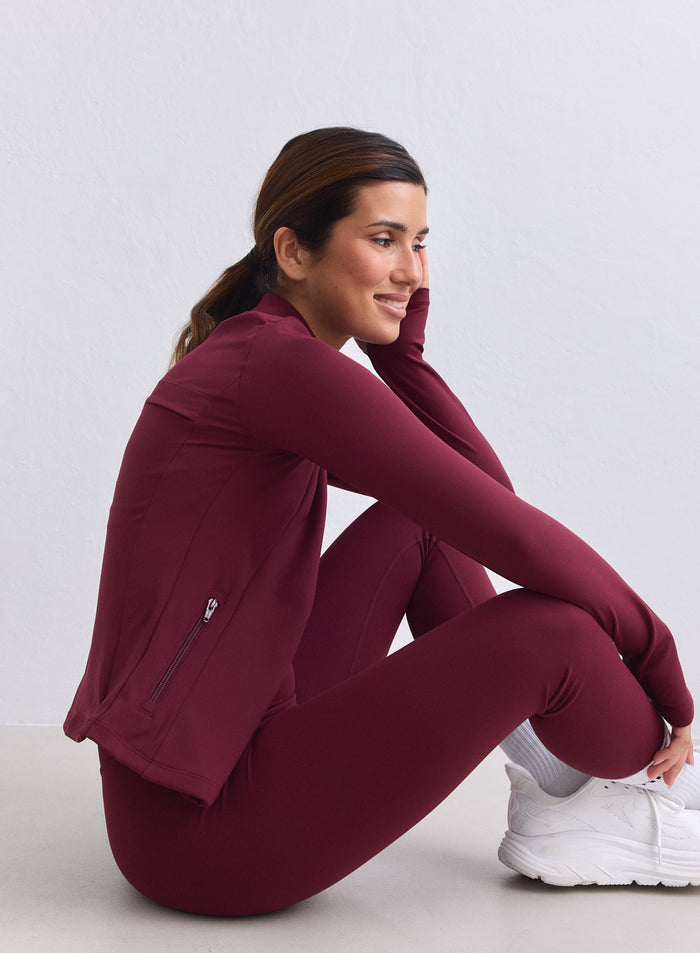 Merlot-värinen aim'n Sense Zip Jacket second skin -tunnulla, kuvattuna sivusta istuvalla mallilla. [XS-165cm]