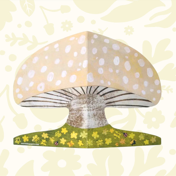 Up close image shows the details of the mushroom shaped greeting card with floral details, ladybirds.