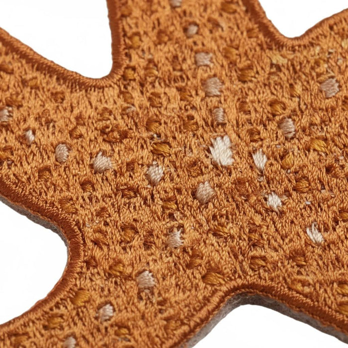 Detailed close-up of Ochre Sea Star Mustard Beetle iron-on patch, textured embroidery, and white thread accents.