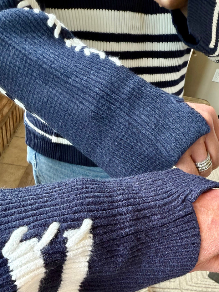 Navy knit sweater sleeve with ribbed cuff and white graphic detail