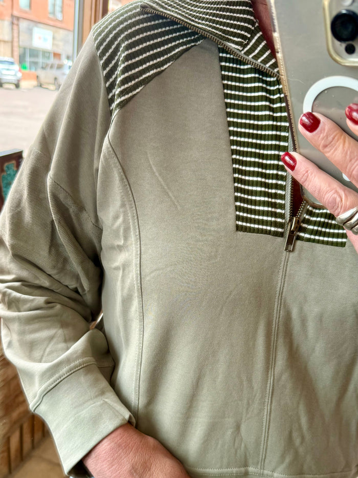 Light olive quarter-zip sweatshirt with striped inner collar and half-open zipper