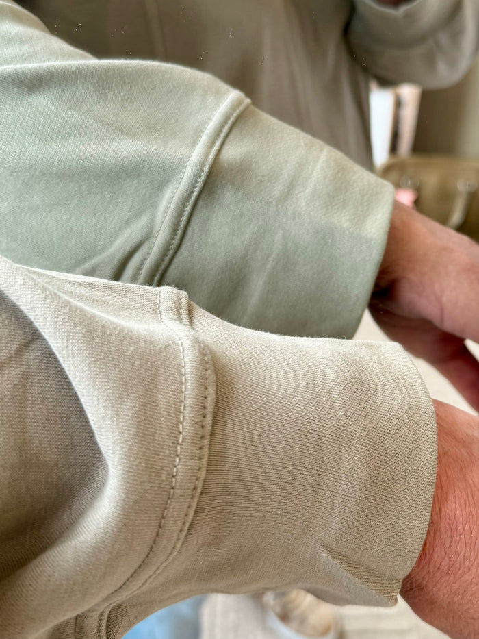 Light olive sweatshirt sleeve with ribbed cuff and visible stitched seam