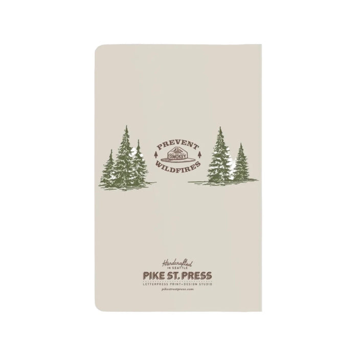 Image shows the back of a notebook with fir trees in green middle left and right with a smokey hat logo in the middle.