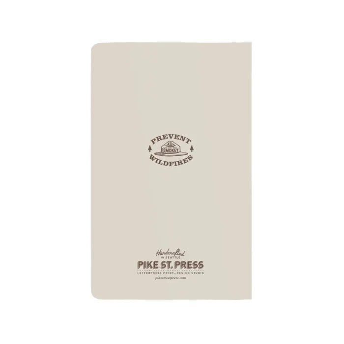 Back of a beige notepad with smokey bear hat motif in brown and prevent wildfires quote.