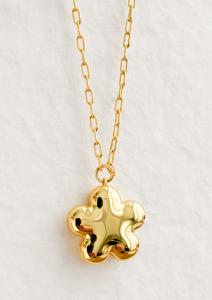 A flower shaped necklace in gold with a puffy look.