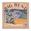 Illustration of a person with a backpack and hat sitting on a hill, looking at mountains with "Big Bend National Park" text above. This artwork is displayed on the Sendero Provisions Big Bend Bandana and printed on silky smooth, organic Japanese cotton for lasting quality.