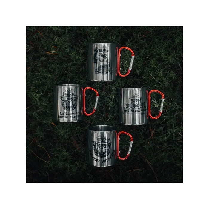 The Smokey Bear Carabiner Handle Mug - Waving Smokey is a silver mug that showcases an illustration of Smokey Bear wearing a ranger hat, featuring a vibrant red carabiner handle to promote wildfire prevention.