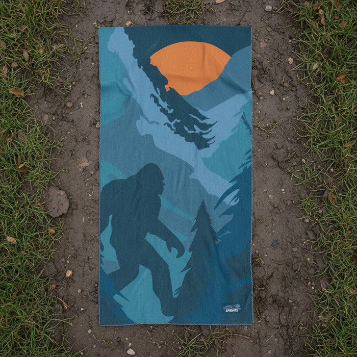 Forager Provisions LTD Sprints Sasquatch Habitat car seat towel with forest, mountain, and Bigfoot print on grass.