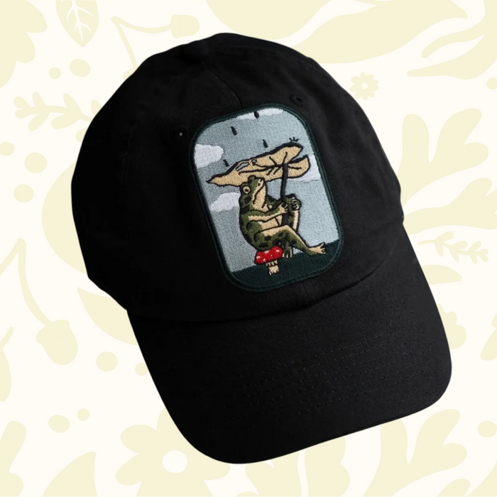 Forager Provisions LTD Stay Home Club black cotton dad hat featuring an embroidered frog with a leaf umbrella patch.