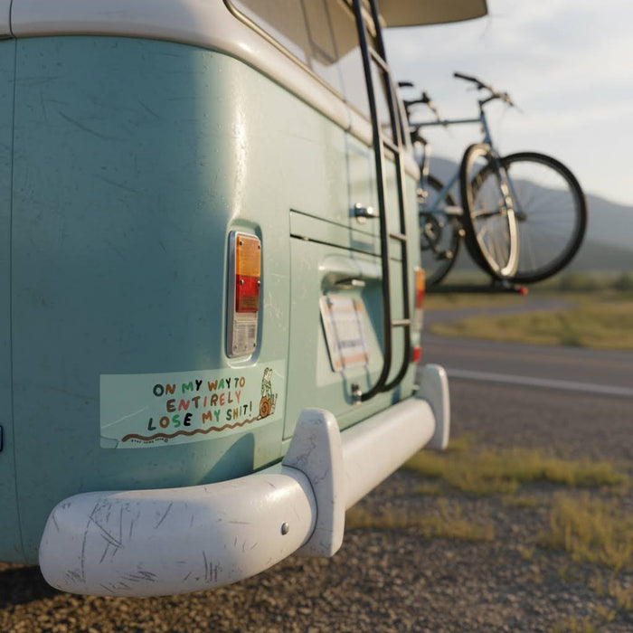 Forager Provisions LTD Stay Home Club bumper sticker on a vintage light blue camper van parked in a scenic landscape.