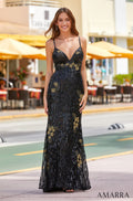 A woman wears a black sequined evening gown with gold floral embellishments, standing on a street with yellow umbrellas.